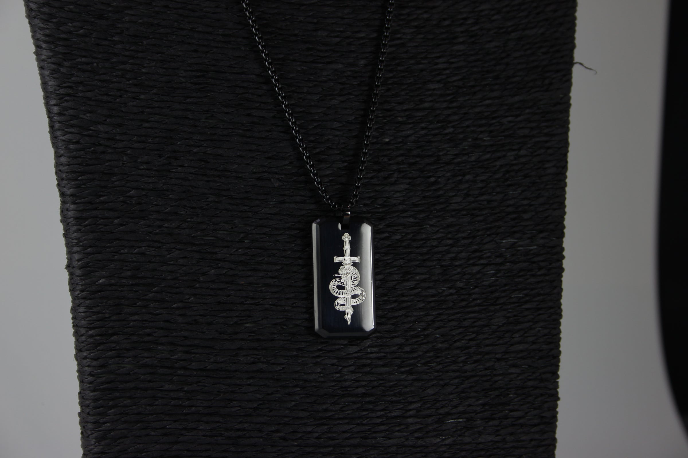 Black textured fabric with a silver pendant on a black chain