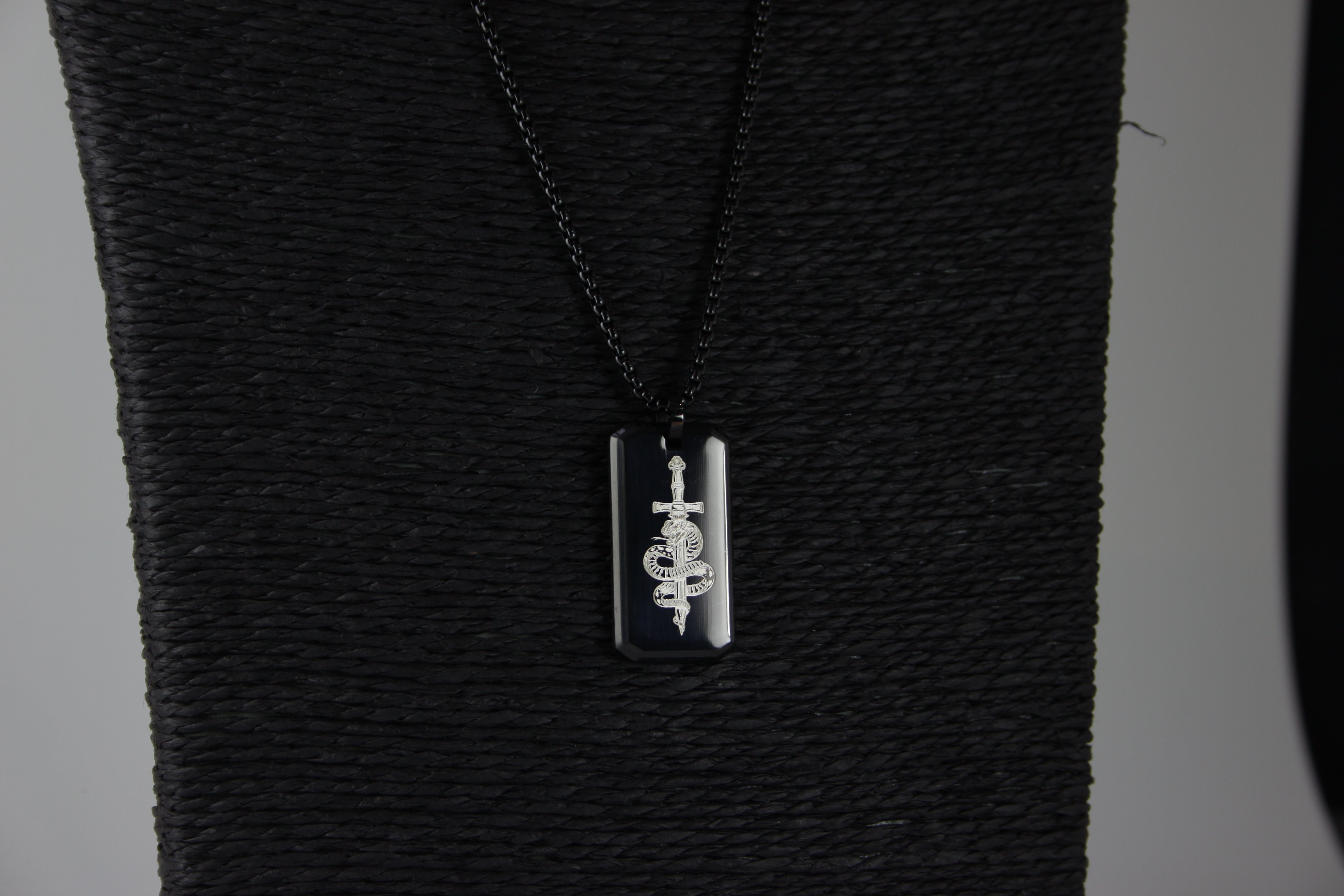 Black textured fabric with a silver pendant on a black chain