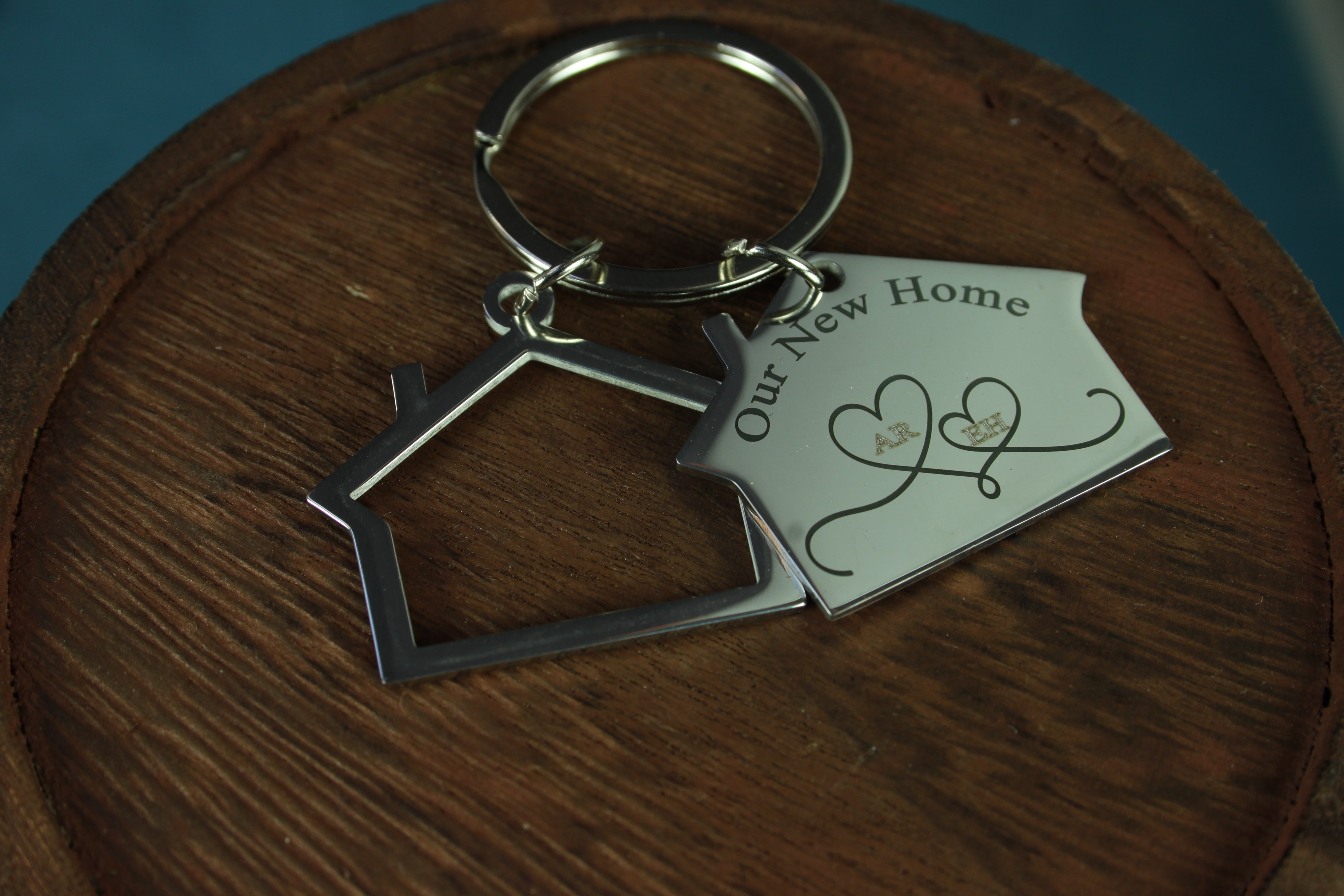 Keychain with house-shaped tag and 'Our New Home' card on a wooden surface