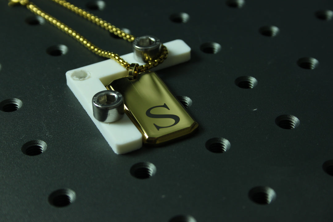 Necklace with a cross pendant and 'S' charm on a black textured background