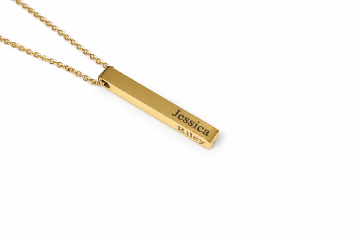 A gold bar necklace with a rectangular pendant engraved with the names &