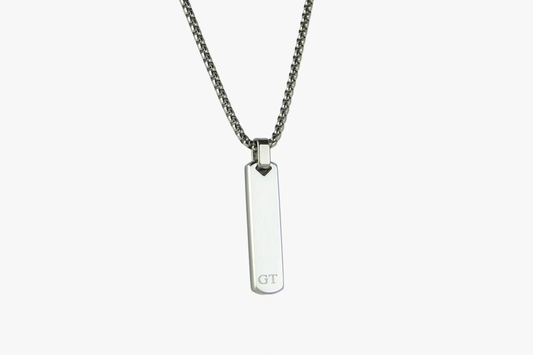 Silver necklace with a rectangular pendant on a light gray background