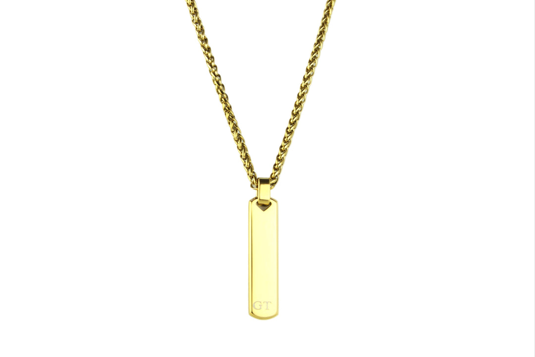 Gold necklace with a vertical bar pendant on a light gray background