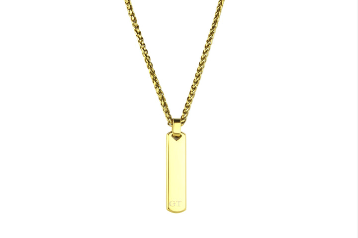 Gold necklace with a vertical bar pendant on a light gray background