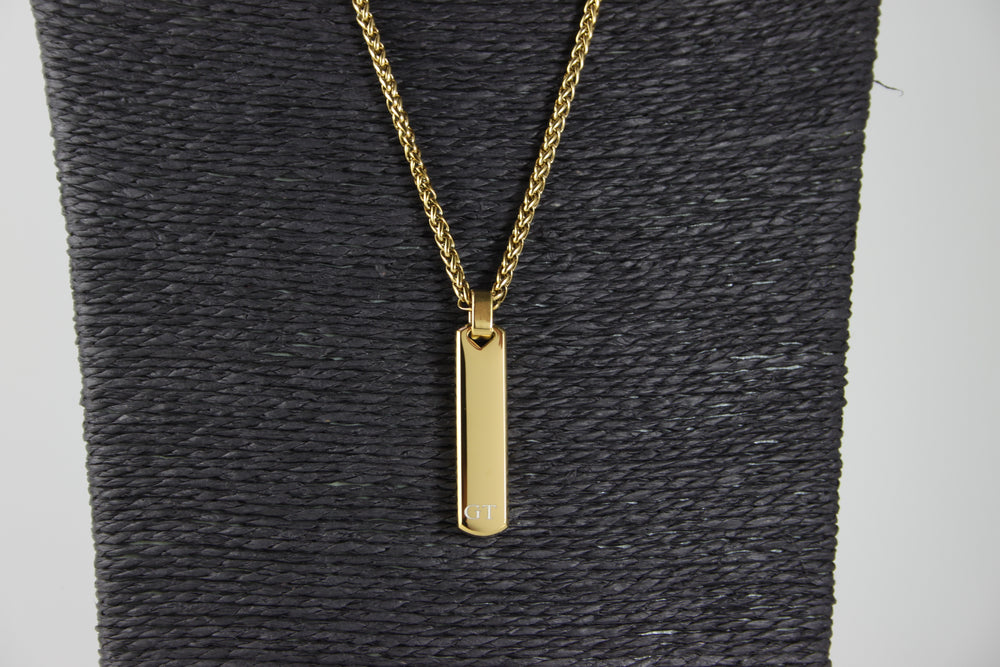 Gold necklace with a pendant on a textured gray surface