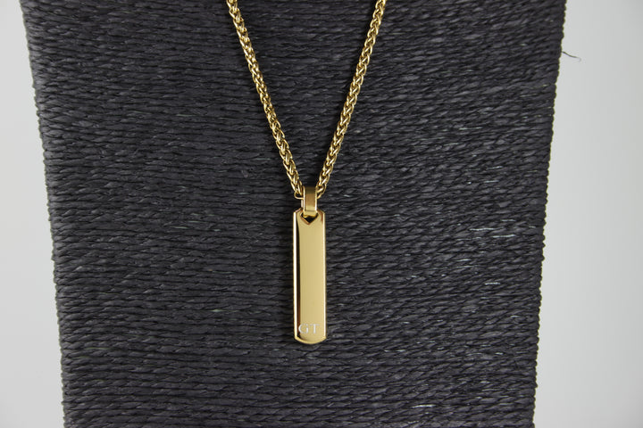 Gold necklace with a pendant on a textured gray surface