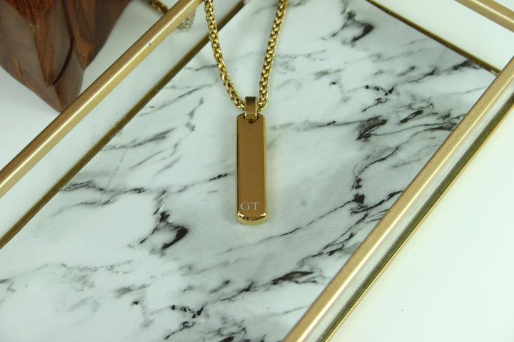 Gold necklace with a pendant on a marble surface