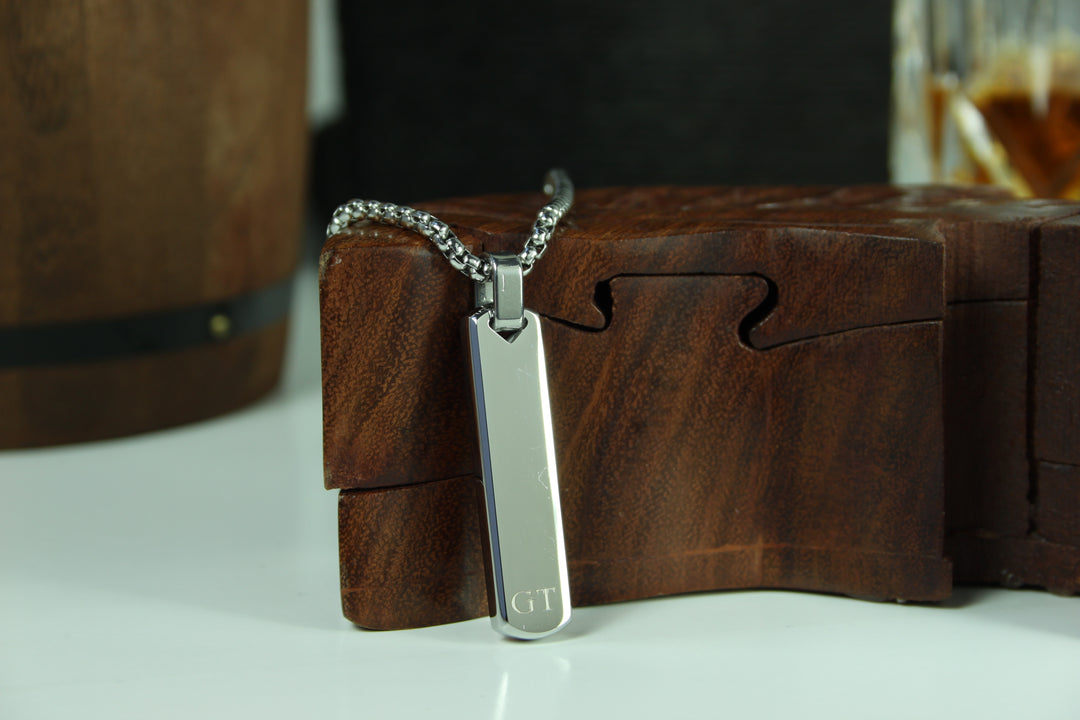 Silver pendant with 'GT' engraving on a wooden box