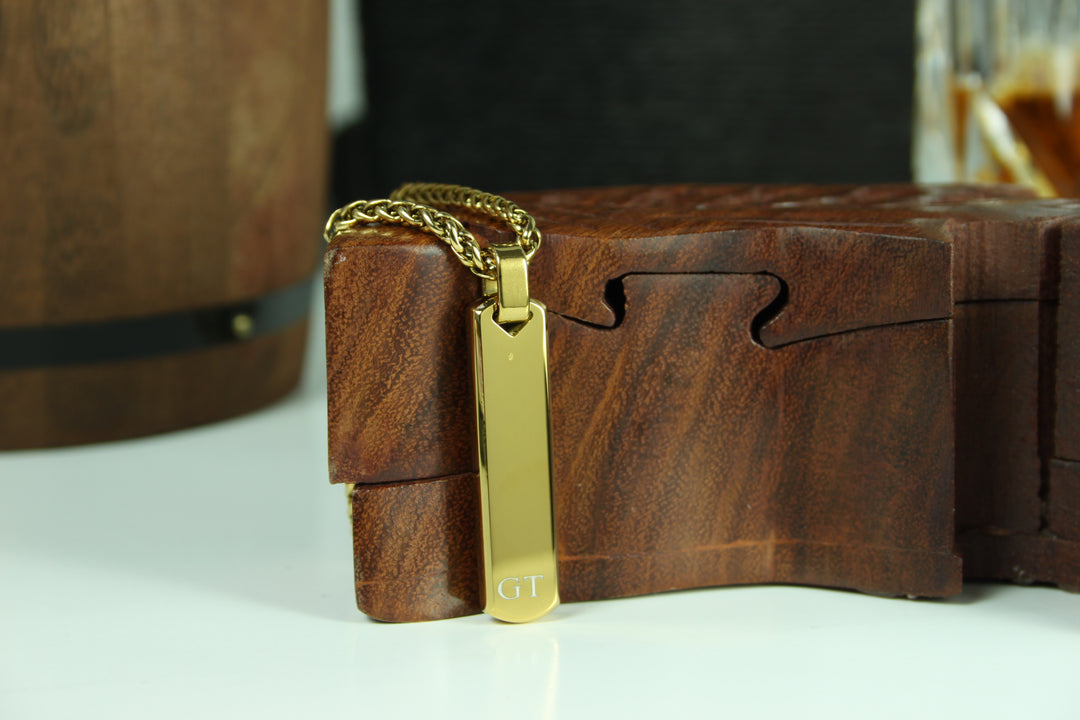 Gold pendant with 'GT' on a wooden box
