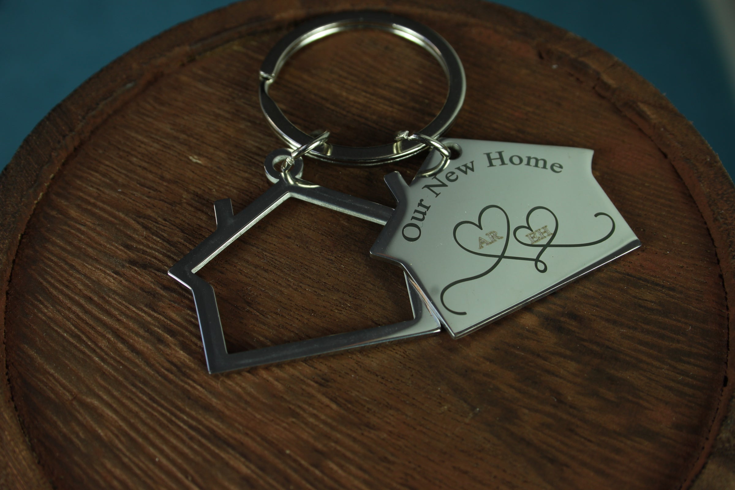 Keychain with house-shaped tag and 'Our New Home' card on a wooden surface