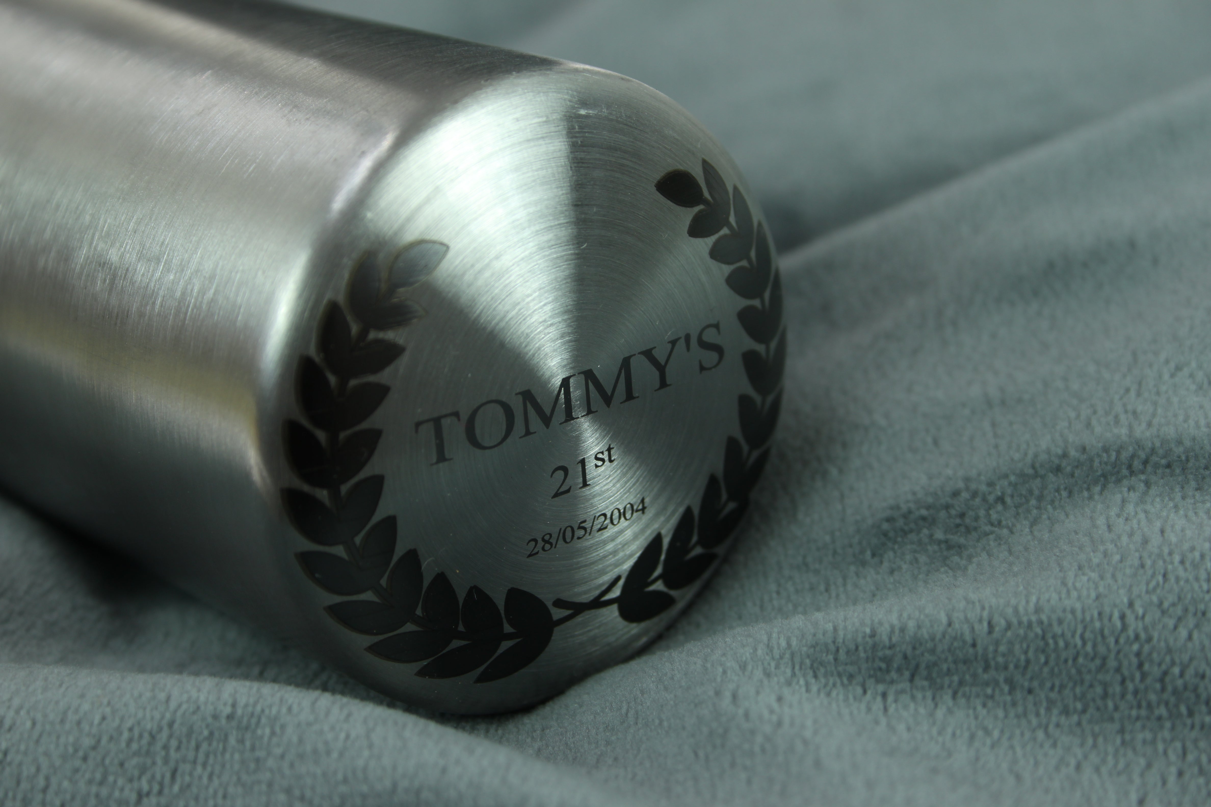 Metallic push Beer bottle opener object with engraved text on a textured fabric background