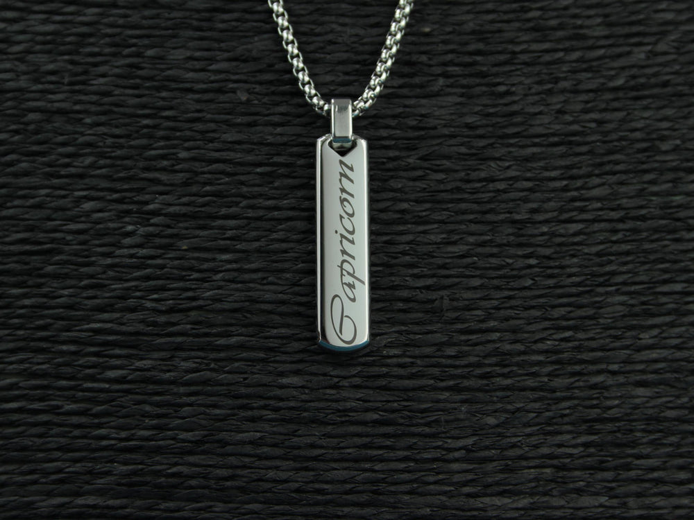 Silver pendant with 'Capricorn' engraving on a black textured background