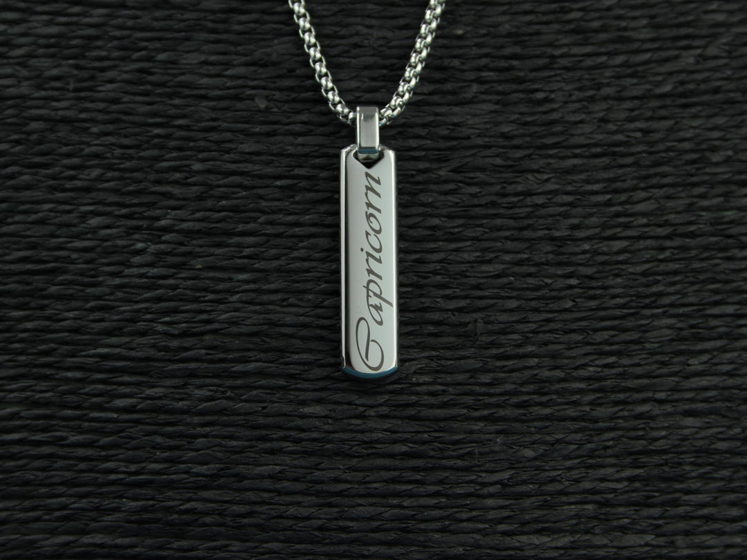 Silver pendant with 'Capricorn' engraving on a black textured background