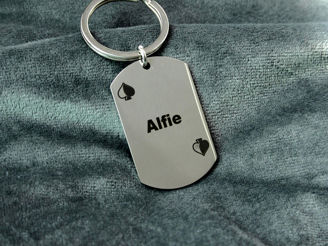 Metal keychain with 'Alfie' engraved on a gray fabric background