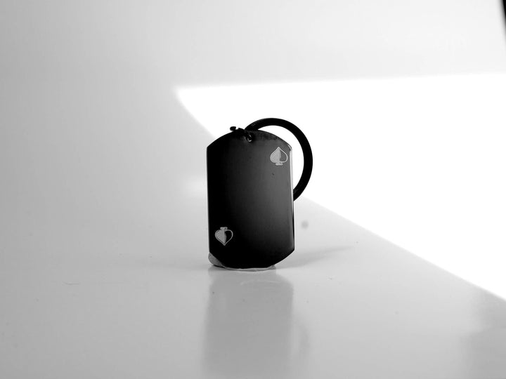 Black pendant keychain on a white surface with a light reflection